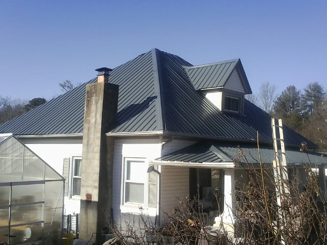 Dark blue standing seam metal roof on a white farmhouse with dormer in Cuttyhunk