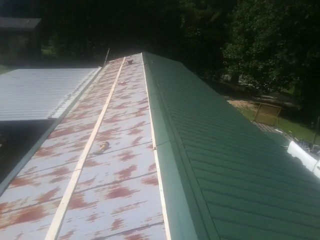 Old rusted panels beside newly installed green metal roofing — Wind Damage Roof Repair by Roofing Brothers in Cuttyhunk