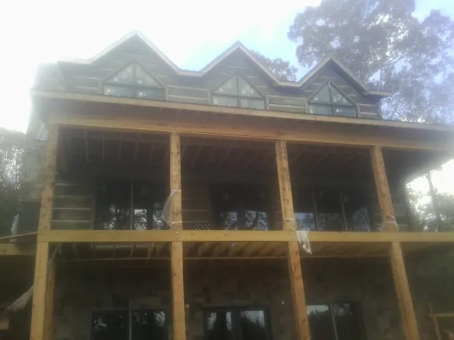 Dormers and porch framing on a large log home under construction — Roof Coating work by our crew in Cuttyhunk