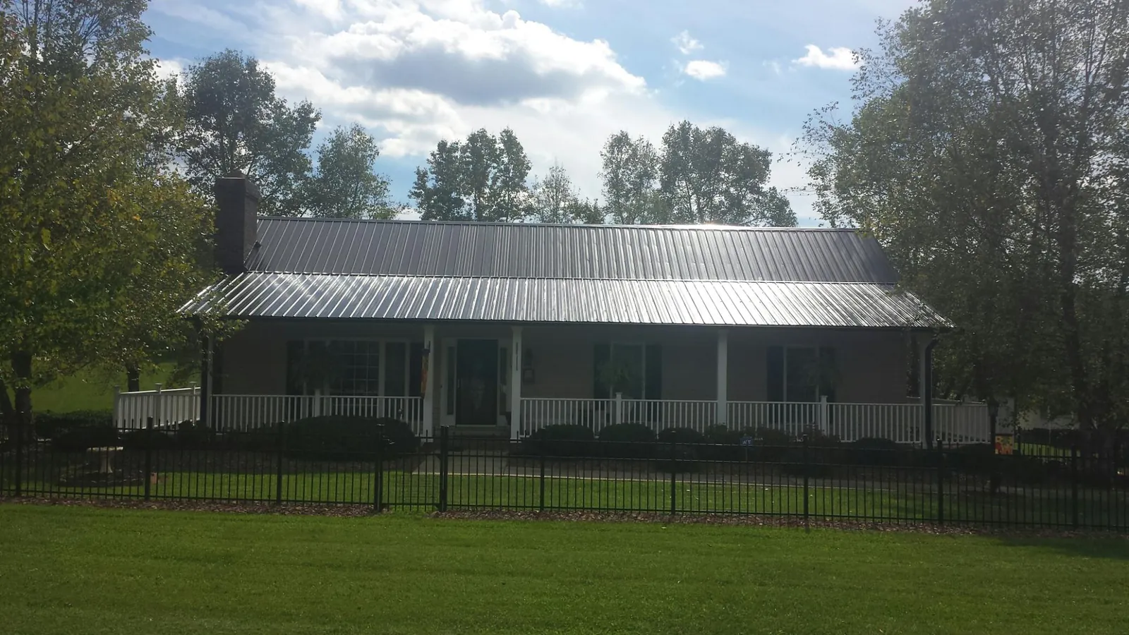 Gray metal roof on a brick ranch with a full width front porch — Gutter Guard Installation work by our crew in Cuttyhunk