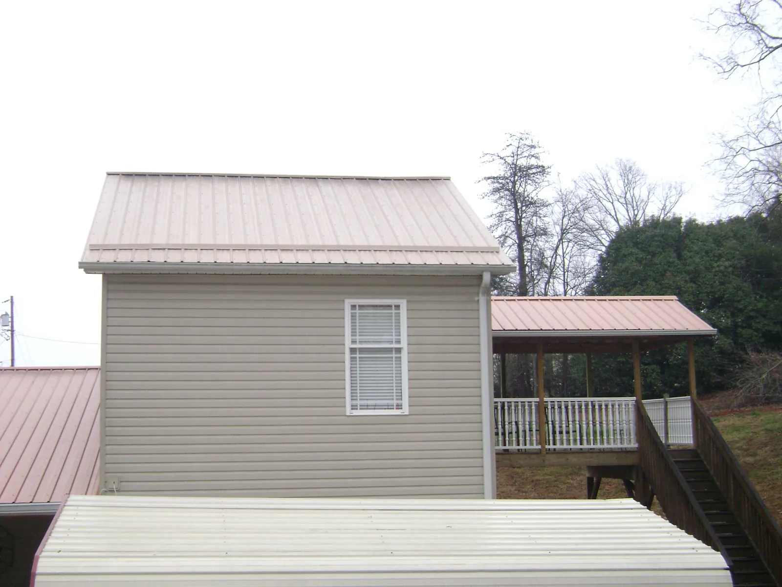 Tan metal roofs on a two story addition and attached porch, from a Roof Replacement job in Cuttyhunk