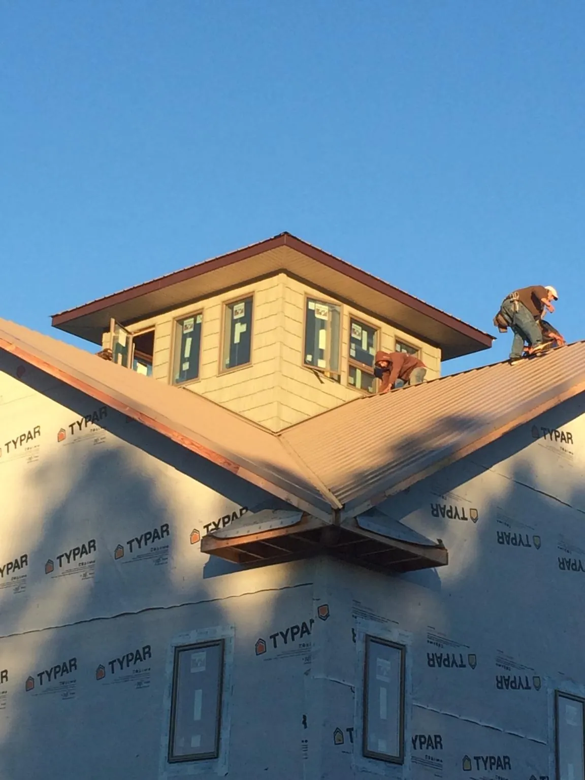 Roofers working around a rooftop cupola on a new metal roof at sunset — Roof Waterproofing in Cuttyhunk by Roofing Brothers